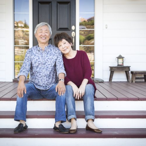 Senior Chinese Couple Sitting on Front Steps of Their House